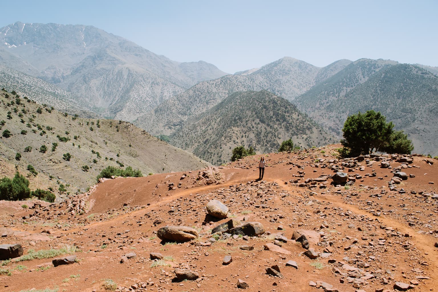 Sarah standing on a dusty hillside with mountains in the background