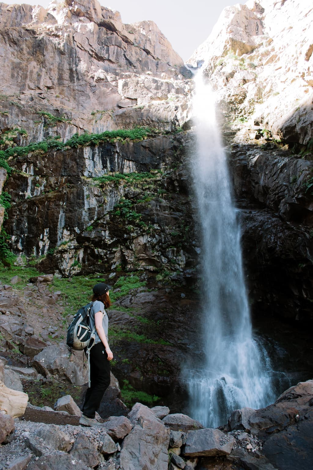 Sarah stands at the foot of a waterfall