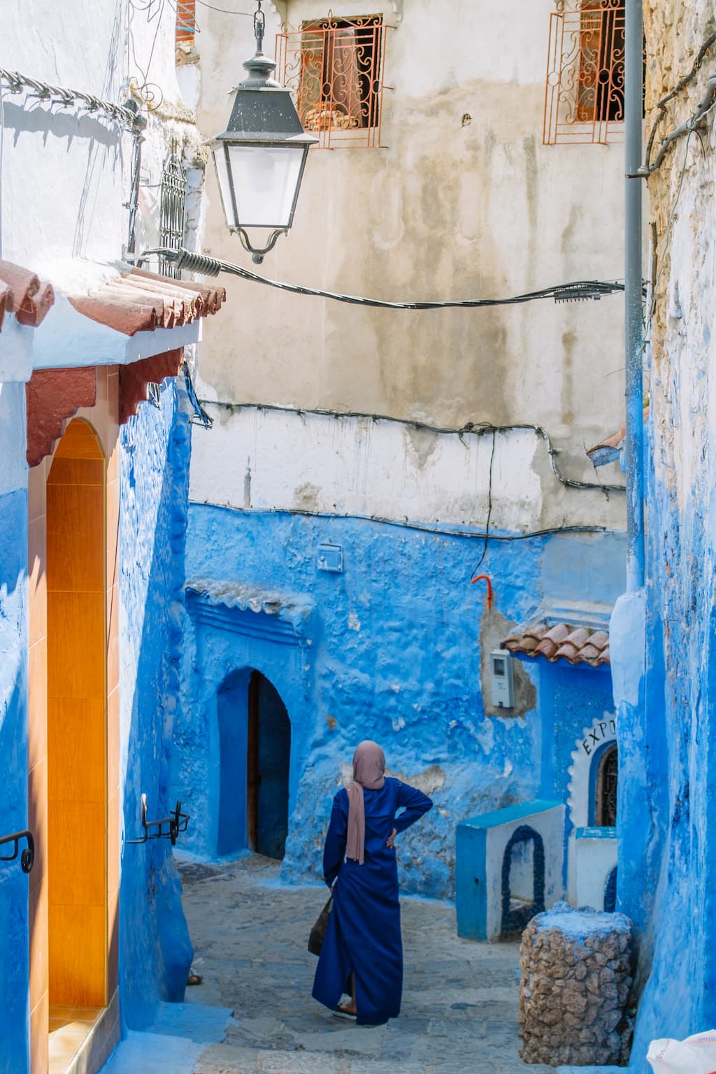 A woman in a blue dress walks down a blue painted street