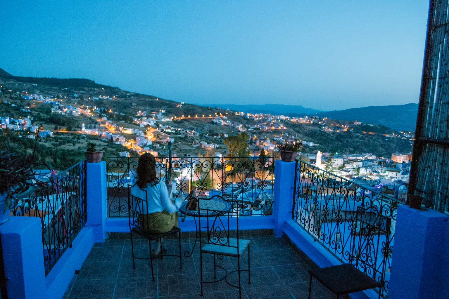 Sarah sitting on a balcony looking out over Chefchaouen at night