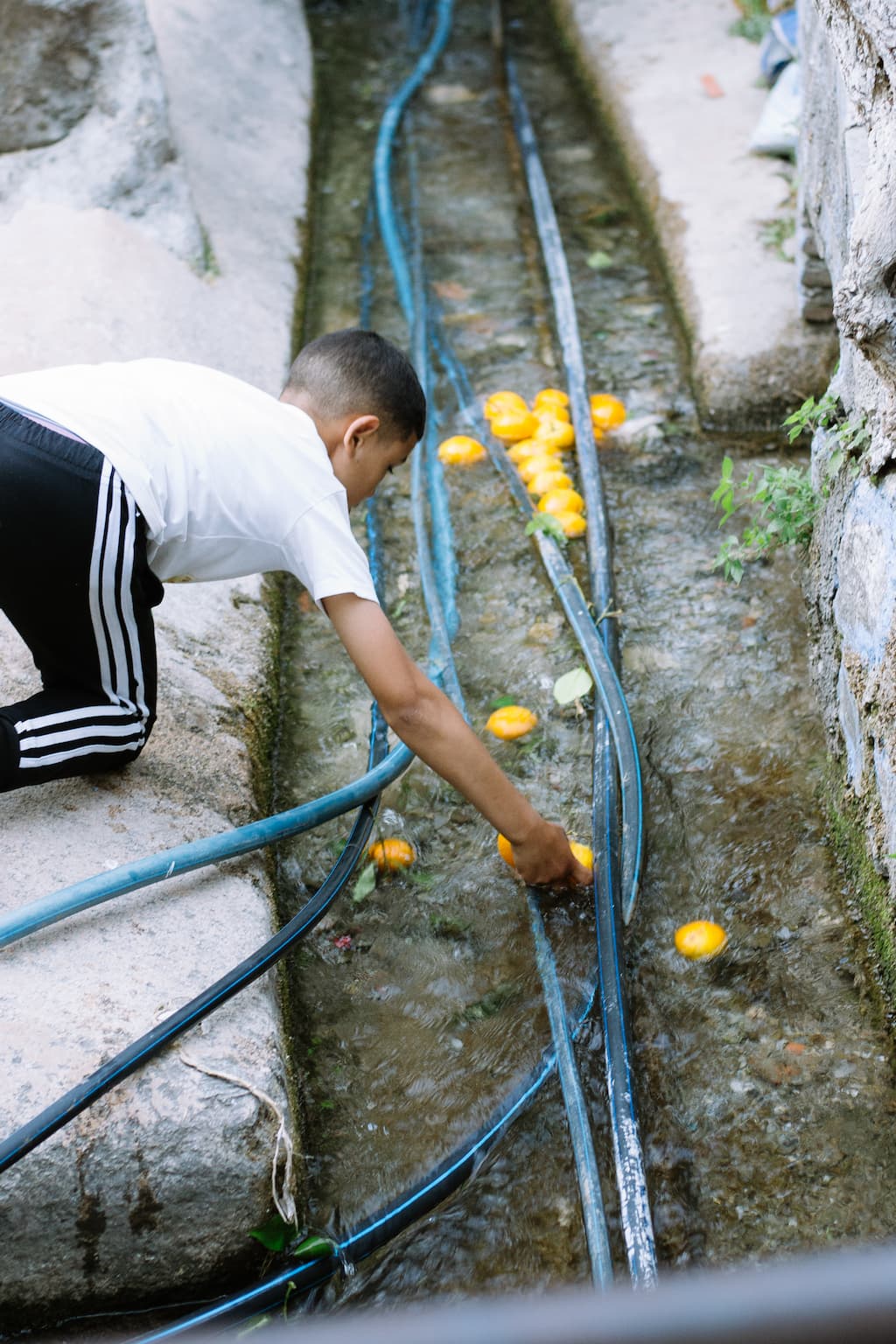 A boy catching oranges which are being washed downstream