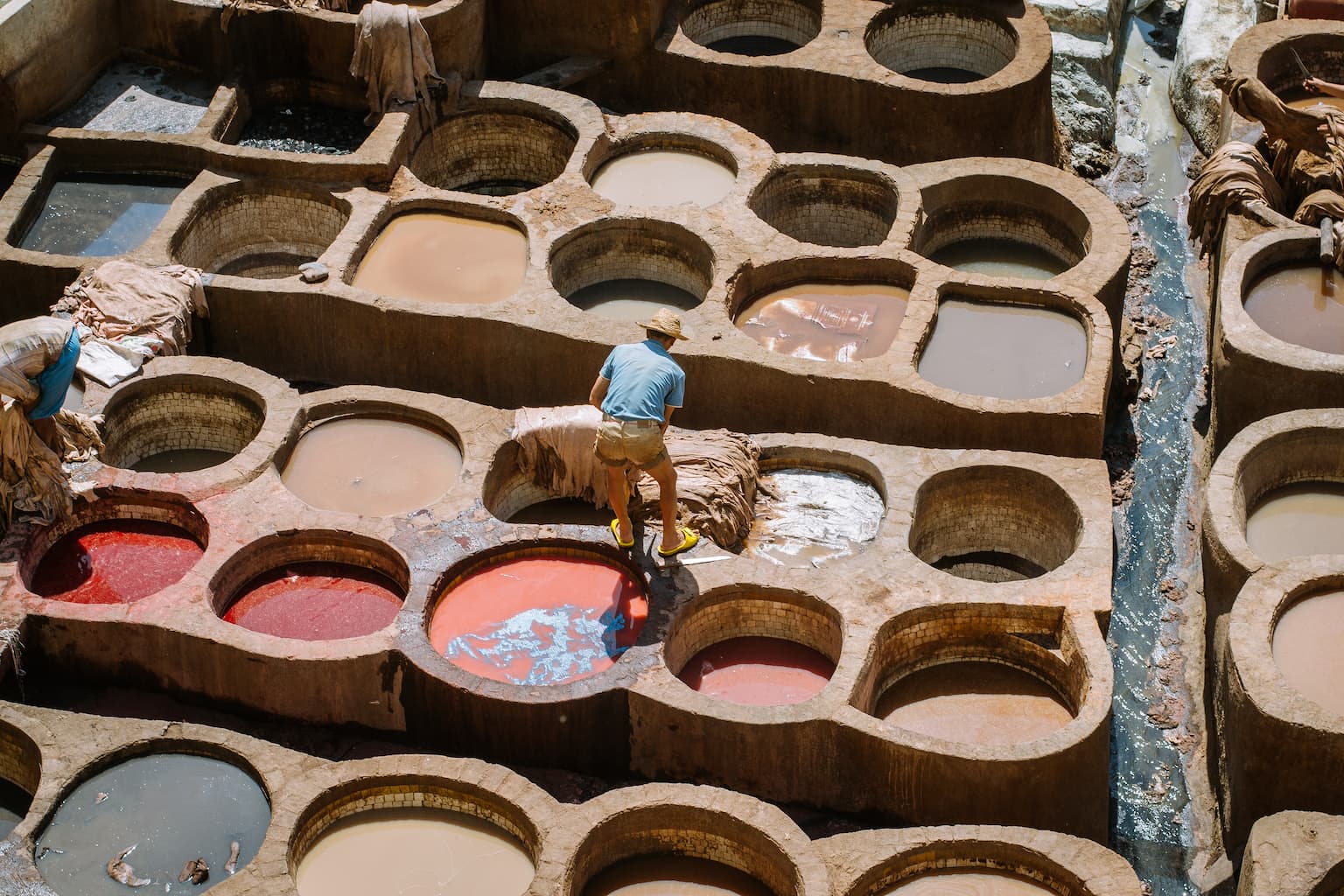 A man working in an open air leather tannery.