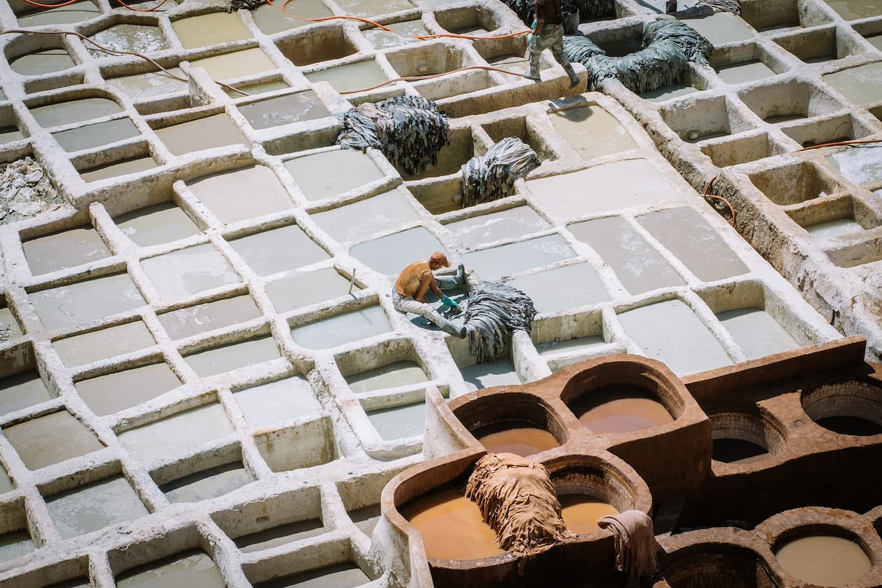 A man working in an open air leather tannery.