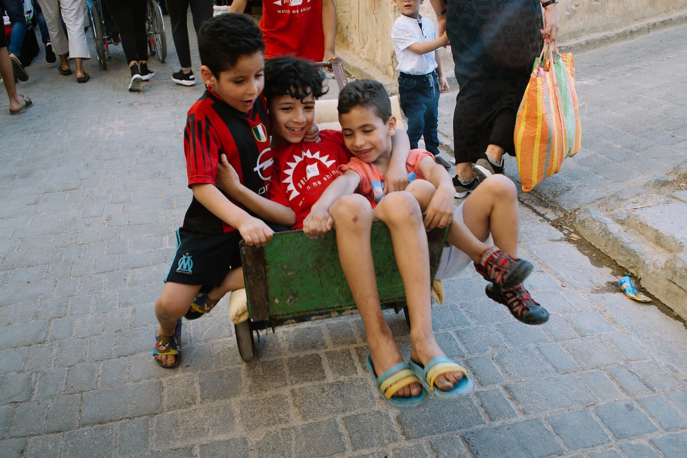 Three children are happy while being pushed along in a wheelbarrow