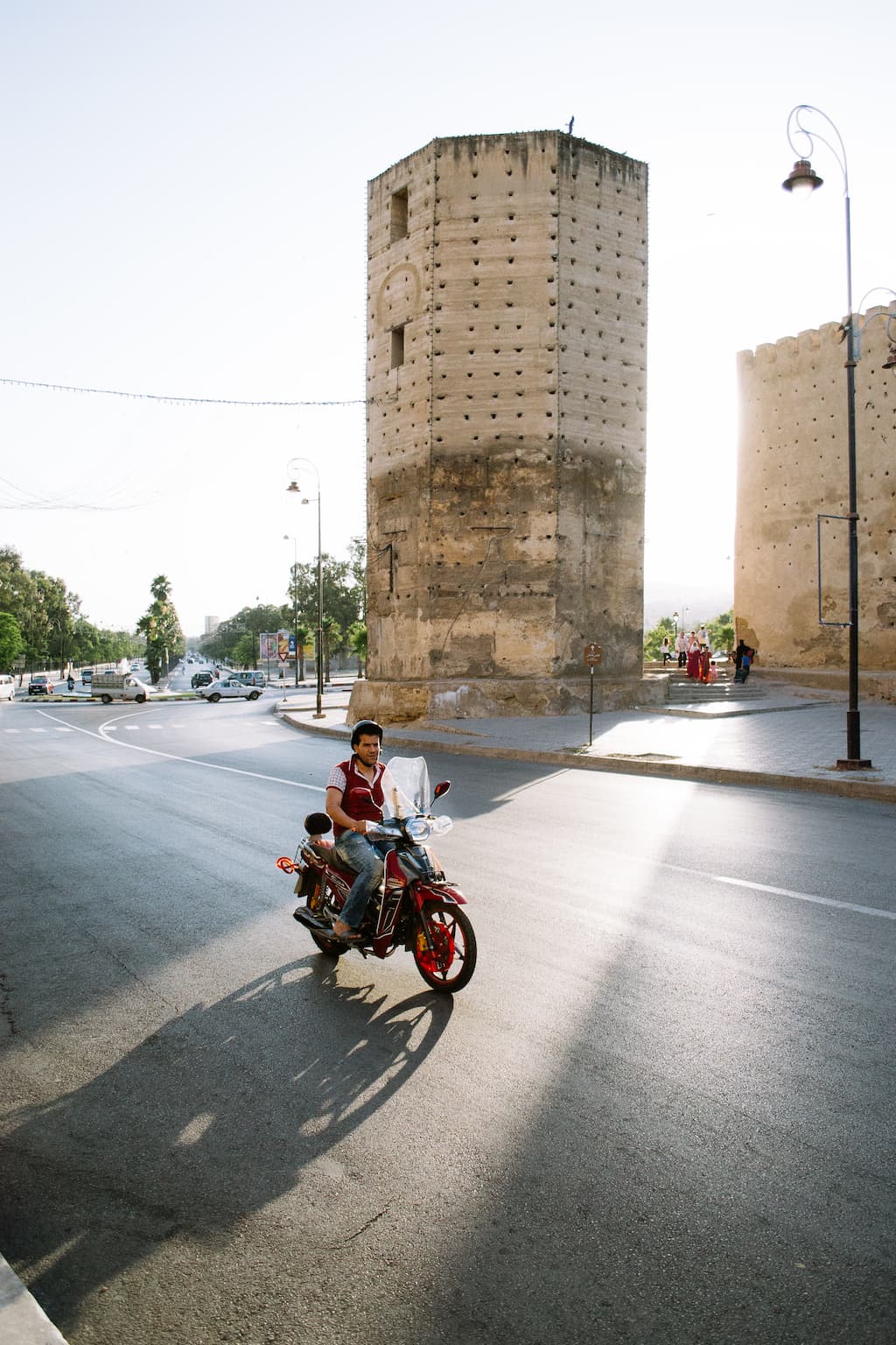 A man on a motorbike is highlighted by the sun behind him