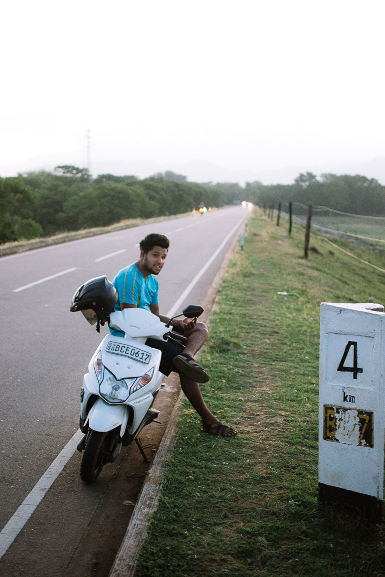 A Sri Lankan man resting on his moped