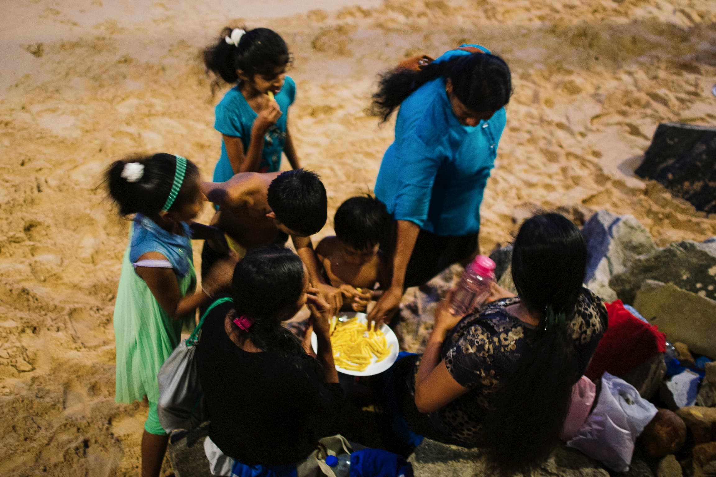 A Sri lankan family eating chips on the beach