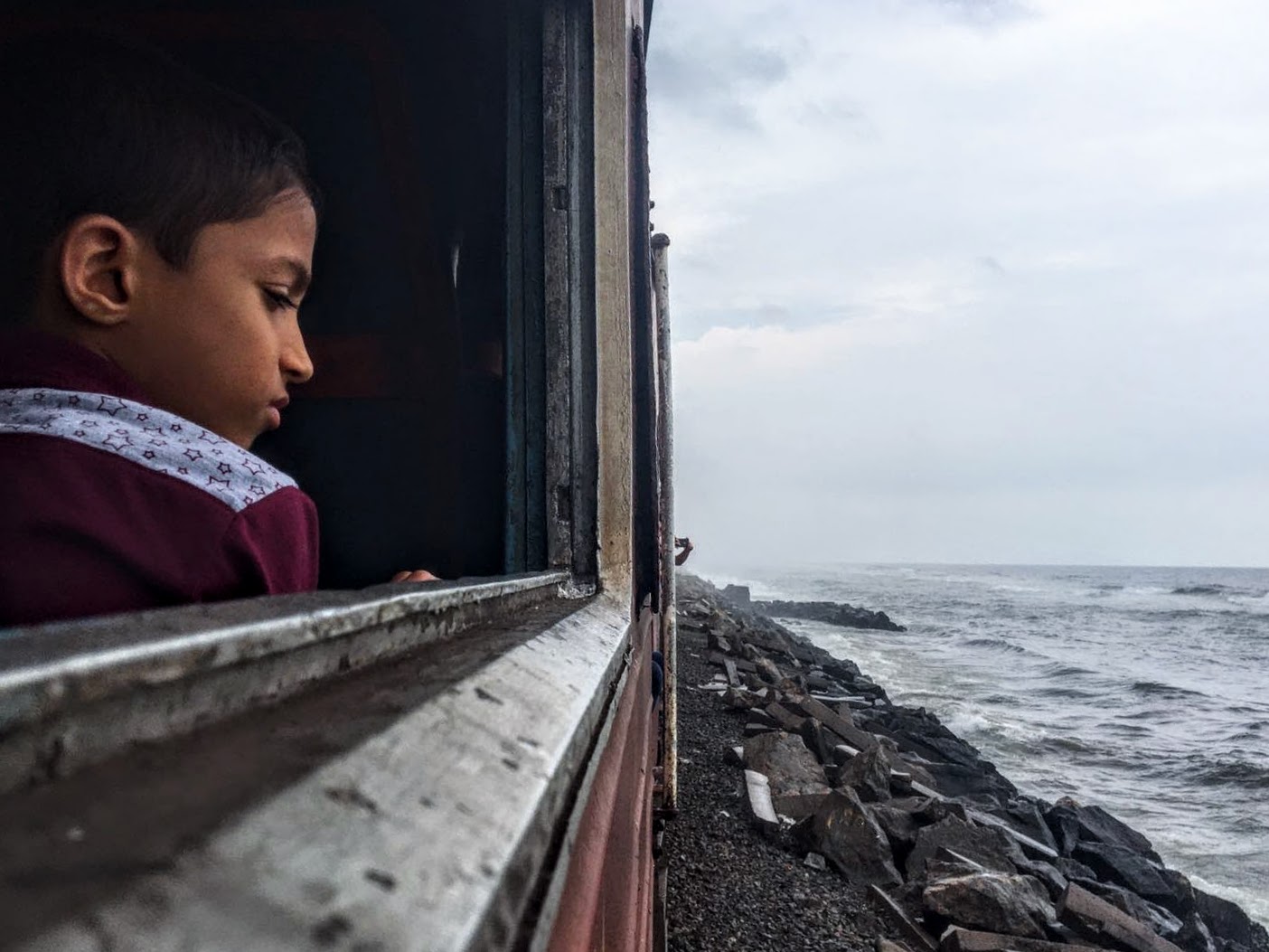 A sri lankan girl looking out the window of a train